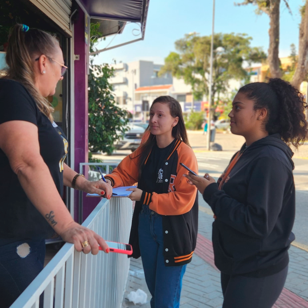 Aluna Gabriela Meiser e Raíssa Viana aplicando questionário com moradora de Camboriú durante a fase de pesquisa de campo do projeto selecionado para a FEBIC 2025 (Foto: Divulgação).